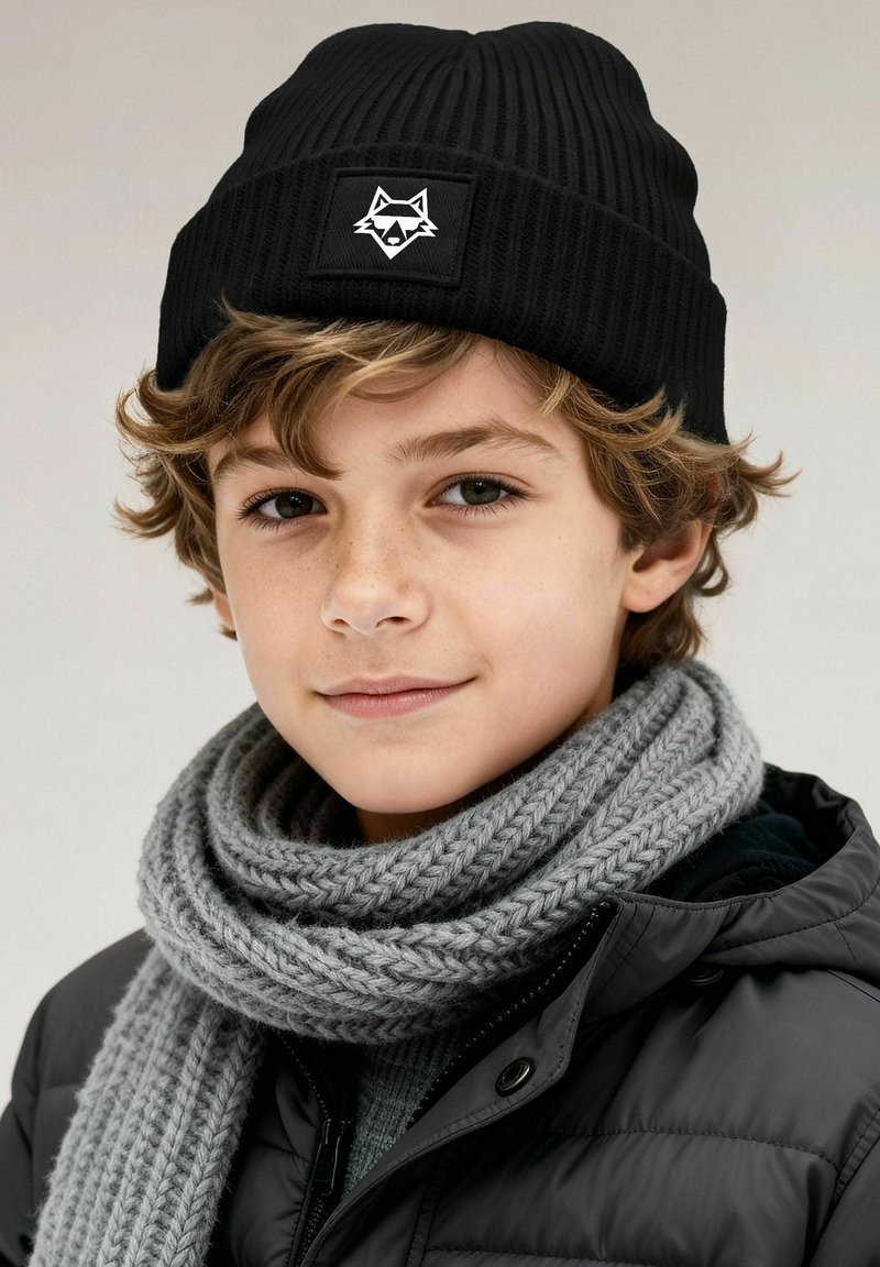 Black ribbed beanie with a white fox emblem, paired with a chunky knitted gray scarf, worn over a black puffer jacket.