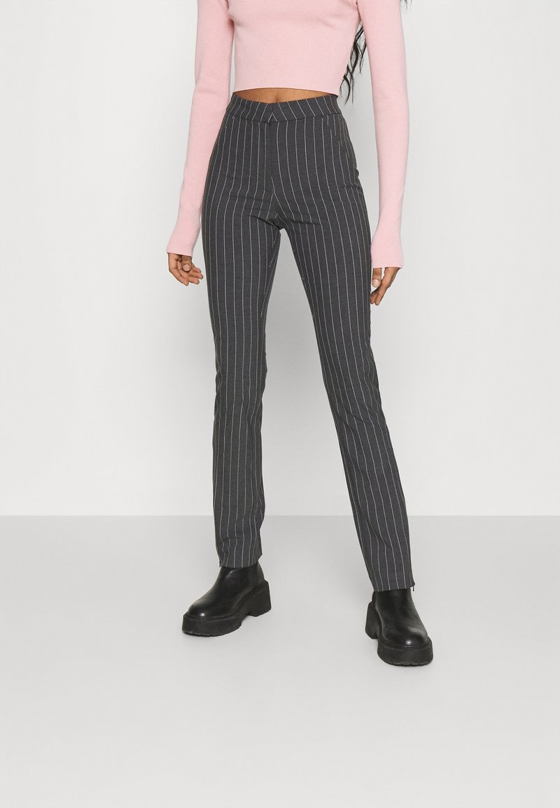 Hoge taille, gestreepte broek in donkergrijs, gemaakt van een gladde stof. Gecombineerd met een lichtroze, lange mouwen crop top en zwarte chunky laarzen.