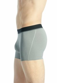 Boxer-briefs gris en matière élastique, avec une taille noire et des coutures contrastées, présentant une silhouette ajustée et une longueur mi-cuisse.