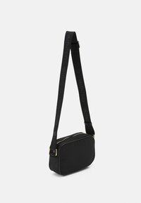 Svart nylonaxelväska med guldfärgad dragkedja, rektangulär form och justerbar rem med "Valentino" präglat i svart.