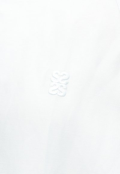 Λευκό ύφασμα με ένα διακριτικό κεντητό λογότυπο που παρουσιάζει ένα αφηρημένο σχέδιο δεμένων σχημάτων σε ανοιχτό νήμα.