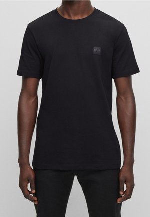 Czarny bawełniany t-shirt z krótkimi rękawami, z małą czarną naszywką w kształcie kwadratu z napisem "BOSS" na piersi. Gładka faktura, regularny krój.