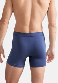 Marineblaue Boxershorts aus dehnbarem Stoff, mit einem glatten Bund und einer figurbetonten Passform, sowie einer schlichten Textur und minimalen Nähten.