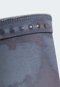 Tmavomodré športové šortky s textúrovaným pásom obsahujúcim kruhové silikónové úchyty. Látka pôsobí hladko s jemnými vertikálnymi pruhmi.