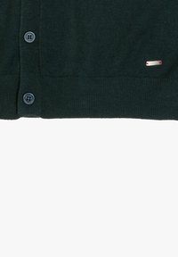 Cardigan verde scuro con una morbida texture, dotato di chiusura con bottoni e di un piccolo dettaglio argentato sull'orlo.