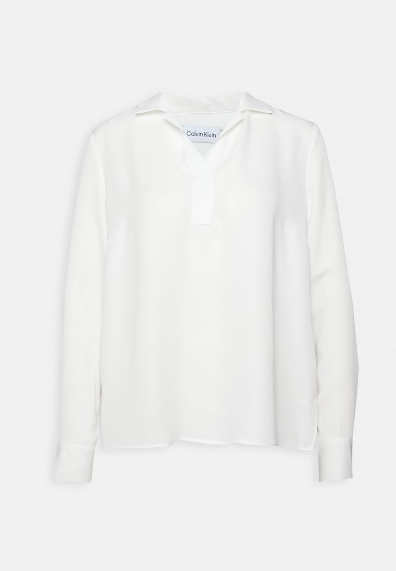 Blusa bianca a maniche lunghe con scollatura a V e colletto, realizzata in tessuto morbido. Presenta polsini con bottone e orlo dritto, design minimalista.