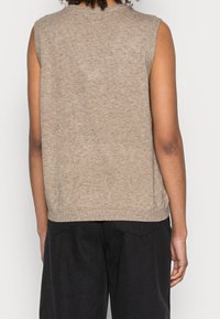 Maglione senza maniche di colore beige, con scollo a girocollo, bordi a coste e vestibilità rilassata, mostrato da dietro.