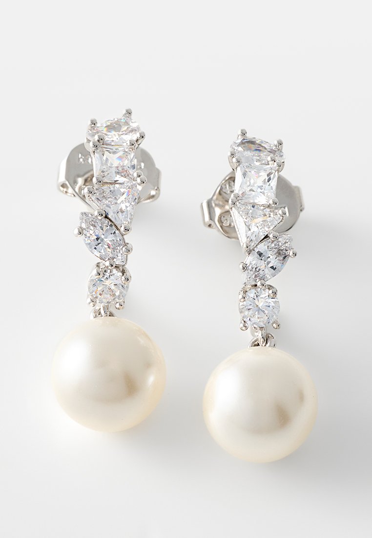 Silberne Ohrstecker mit mehreren klaren Edelsteinen über großen runden weißen Perlen auf einem hellen Hintergrund.