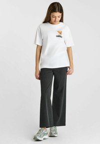 T-shirt en coton blanc à manches courtes avec un design brodé ludique et le mot "CERISES." Associé à un pantalon à rayures charpenté taille haute.