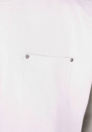 Un pull en tricot rose clair avec une petite poche poitrine, doté de deux boutons-pression en métal. Texture douce et design simple.