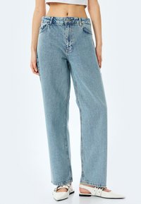 Jean taille haute bleu clair à coupe décontractée, avec un design à cinq poches et un léger délavage sur les cuisses.