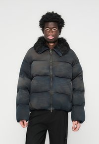 Blue puffer jacket with a fur collar, featuring a zip front, boxy shape, and quilted design. The fabric has a subtle texture and pattern.