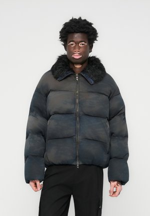 Blue puffer jacket with a fur collar, featuring a zip front, boxy shape, and quilted design. The fabric has a subtle texture and pattern.