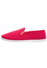 Červená plátěná obuv na slip-on s bílou gumovou podrážkou a elastickými bočními detaily s pruhovaným vzorem. Hladký povrch, nízký profil.