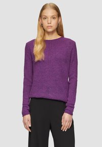 Pull en maille violet avec un col rond, des manches longues et un motif texturé subtil. Associé à un pantalon noir. Coupe lisse, légèrement ample.