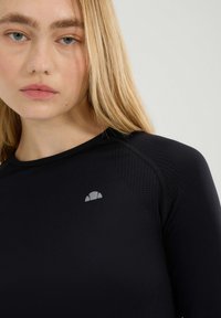 Zwarte sporttop met lange mouwen, met gestructureerde panelen en een klein grijs logo op de borst. Glad materiaal met een aansluitend ontwerp.