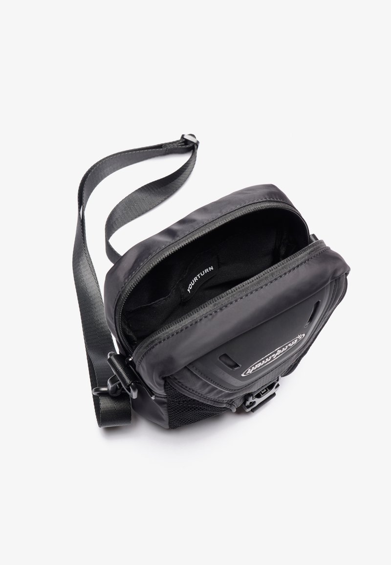 Bolso cruzado negro con un compartimento principal con cremallera, bolsillo lateral de malla y correa ajustable. Material suave con acentos texturizados.