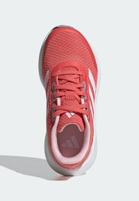 Koralowy but sportowy z fakturowaną cholewką, białym wzorem z trzema paskami i wyściełanym kołnierzem. Posiada dopasowane sznurówki i gumową podeszwę.