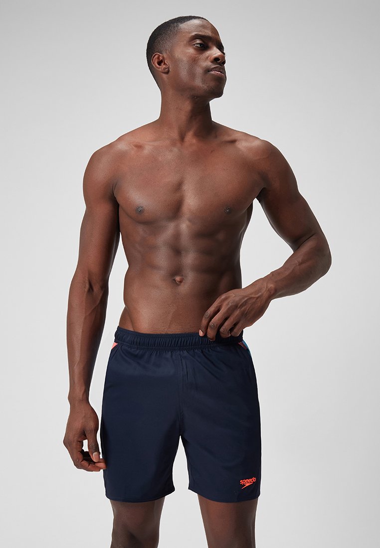 Granatowe szorty kąpielowe z elastycznym paskiem i pomarańczowym detalem, wykonane z lekkiego materiału. Długość do połowy uda z luźnym krojem.