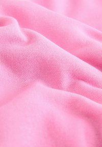 Mäkká, textúrovaná tkanina v žiarivej ružovej farbe, s hladkým, elastickým úpletom, viditeľnými vláknami a jemným splývaním.