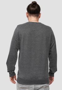 Grijze sweatshirt met een gestructureerde afwerking, ribbelmanchetten en onderrand. Beschikt over een ronde hals en een eenvoudig ontwerp zonder zichtbare patronen of logo's.
