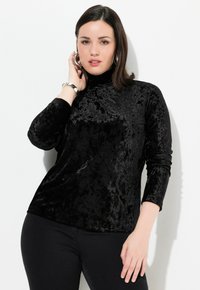 Schwarzes Samtoberteil mit langen Ärmeln und hohem Kragen; weiche Textur und leichtem Glanz. Verfügt über einen lockeren Schnitt und minimale Nahtdetails.