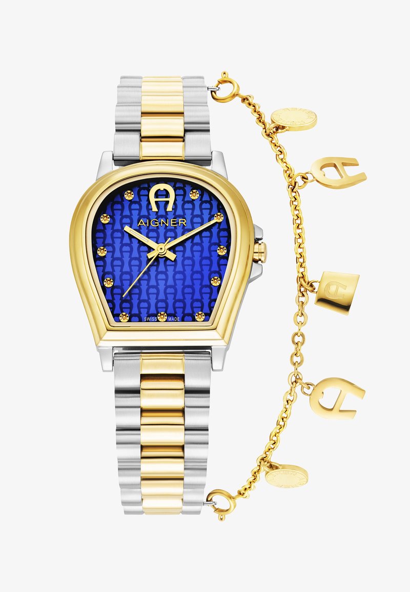 Reloj de acero inoxidable en oro y plata con una esfera azul con patrón, marcadores de hora dorados y una cadena decorativa con charms del logo.