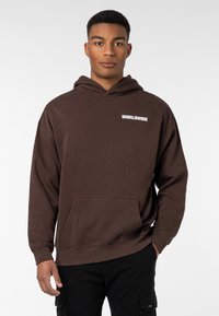 Brauner Hoodie mit einer Kängurutasche, auf der die Aufschrift "WORLDWIDE" in Weiß auf der linken Brustseite gedruckt ist. Weicher Stoff, lockere Passform.