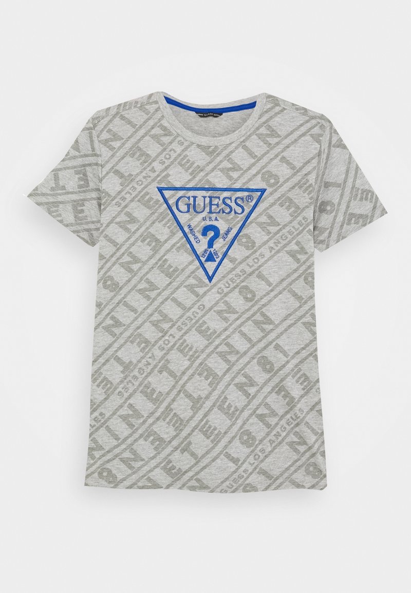 T-shirt gris clair à manches courtes avec motif de texte en diagonale et triangle du logo Guess bleu avec un point d'interrogation sur la poitrine.