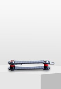 Verktyg av kolfiber med en slank, förlängd form. Utrustad med röda accenter, silverfärgade detaljer och en strukturerad yta för grepp.