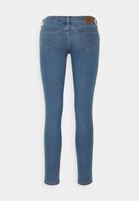 Vaqueros skinny de mezclilla azul con una cintura de altura media, que cuentan con dos bolsillos traseros y detalles de costura sutiles. Textura suave, corte a la altura del tobillo.