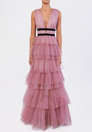 Robe en tulle rose à étages sans manches avec un décolleté en V profond et des bandes noires à la taille, portée par une personne debout sur un fond blanc uni.