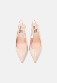 Μπεζ ψηλοτάκουνα πέδιλα με λουράκι στην πλάτη από πατέντα δέρμα, με μυτερή μύτη και σχέδιο με ανοίγματα. Διαθέτουν επενδύσεις με λογότυπο, λεία υφή και μινιμαλιστική σιλουέτα.