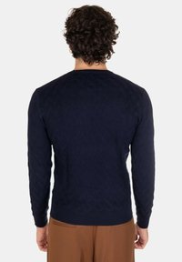 Maglione blu navy con un motivo a diamante testurizzato, maniche lunghe e scollo rotondo, realizzato in un materiale a maglia.