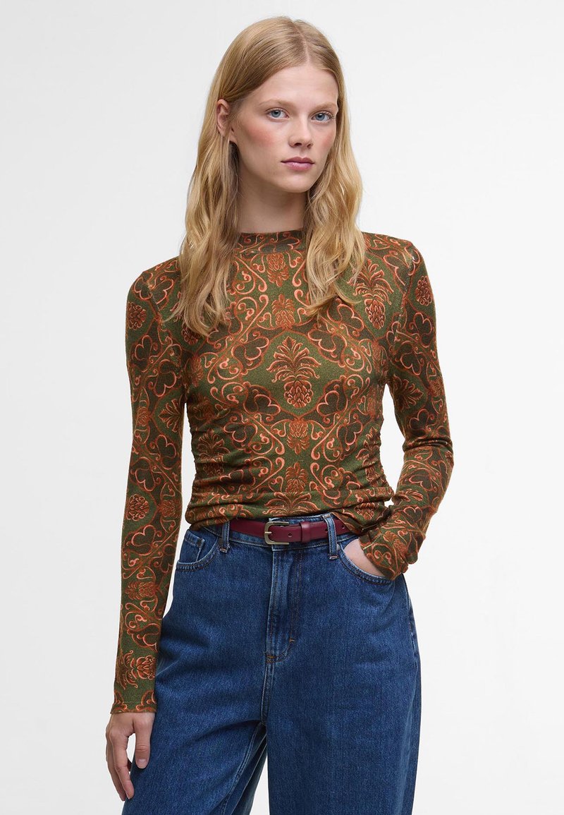 Langarmtop in donkergroene stof met een oranje bloemenpatroon, voorzien van een ronde hals en een getailleerd ontwerp, gecombineerd met high-waisted blauwe jeans.