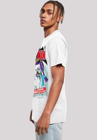 White t-shirt featuring comic book graphic design with colorful characters and text. Short sleeves, round neckline, relaxed fit.