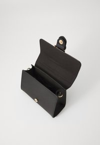 Sac à main en cuir noir avec un design structuré, accents en matériel doré et fermeture à pression magnétique. L'intérieur présente un compartiment unique.