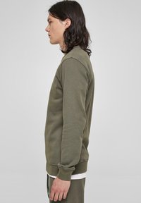 Olijfgroen sweatshirt met een ronde hals, lange mouwen, ribgebreide manchetten en onderrand, gemaakt van een zachte stof met een casual pasvorm.