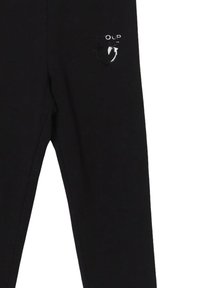 Leggings neri con una superficie liscia, dotati di un logo metallico sulla parte superiore sinistra. Realizzati in tessuto elasticizzato per comfort e vestibilità.