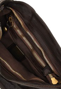 Interno di borsa in pelle marrone con più tasche con cerniera, cerniere dorate e una texture liscia. Foderata con tessuto marrone e dotata di etichetta con il marchio.