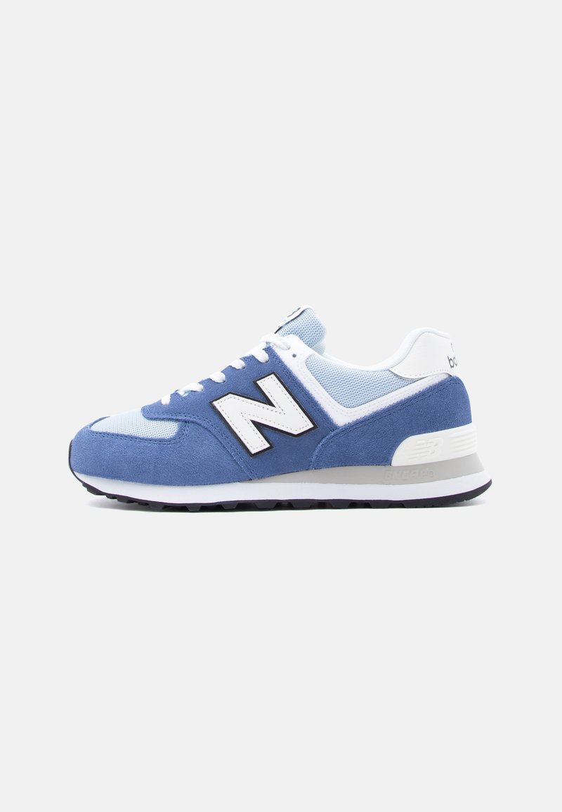 Baskets New Balance bleues et blanches avec dessus en daim et maille, lacets blancs et semelle en caoutchouc noire, vues de profil.