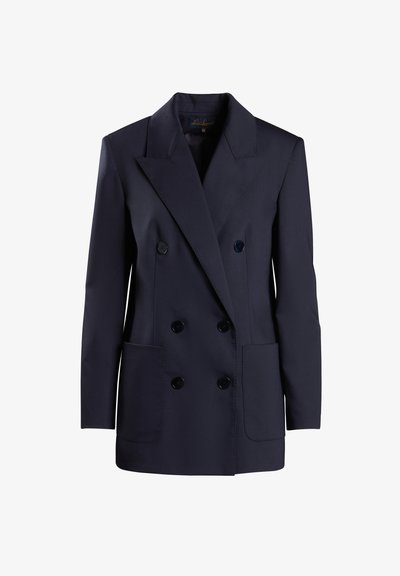 Laivansinis kaksirivinen blazer, joka on valmistettu sileästä kankaasta ja jossa on suuret etutaskut sekä erottuvat liepeet. Napit ovat tummat ja pyöreät.