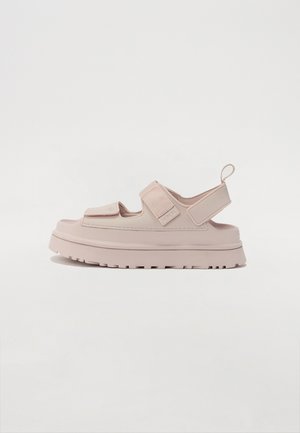 Lys rosa gummisandaler med en chunky såle, justerbare stropper og en hæltabs. Har en teksturert overflate og minimalistisk design.
