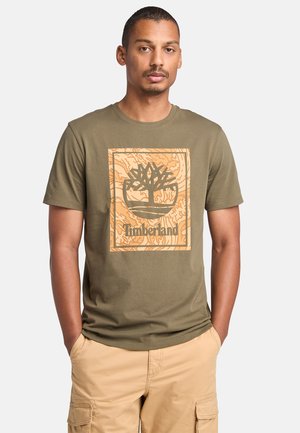 Camiseta de algodón color verde oliva con un gran gráfico del logo de Timberland en beige centrado en el pecho, cuello redondo y mangas cortas.
