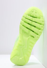 Bright green Nike sneaker sole angled upright, showing tread pattern and mesh details on white background.