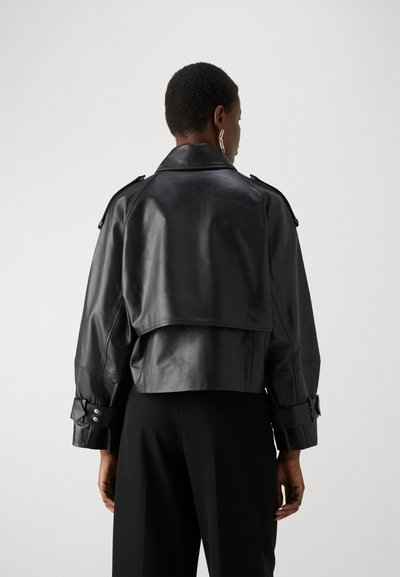 Μαύρο δερμάτινο κοντό μπουφάν με φαρδύ γιακά, κουμπωτές μανσέτες και σχεδίαση με επίστρωση στην πλάτη. Λείος υφασμάτινος σχεδιασμός με ελάχιστες μεταλλικές λεπτομέρειες.