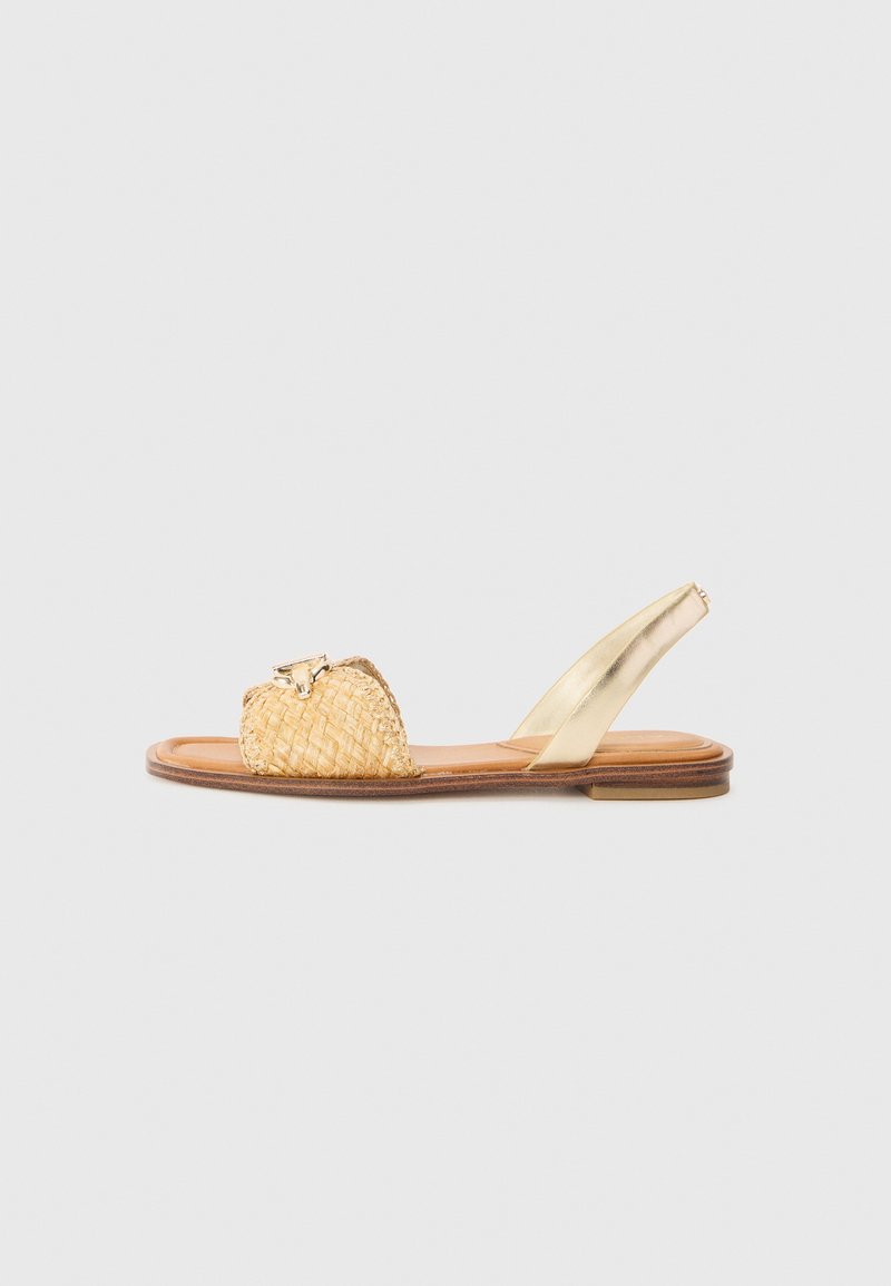 Sandalo in paglia intrecciata di colore naturale con una fascia metallica dorata, suola piatta e dettagli decorativi sulla parte anteriore.