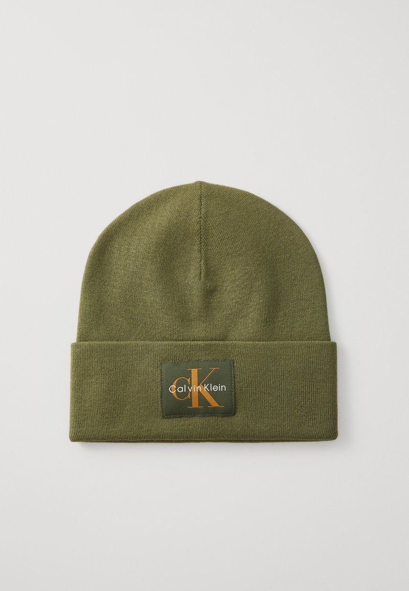 Cappello di maglia verde oliva con risvolto, dotato di un'etichetta rettangolare che mostra il logo "Calvin Klein" e "CK" in arancione.