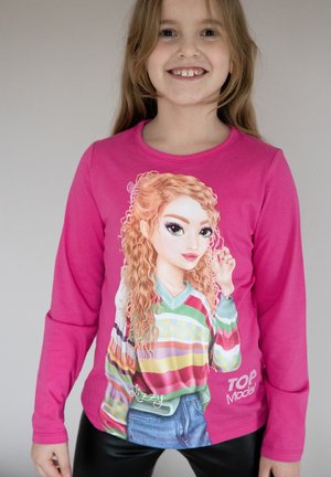 Maglietta a maniche lunghe rosa con una grafica colorata e illustrata di un personaggio, completa di dettagli sui capelli e sui pattern degli abiti. Vestibilità casual.