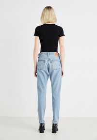 Lichtblauwe jeans van denim met een relaxte pasvorm, voorzien van een lederen achterpatch, twee achterzakken en een licht vervaagde textuur.